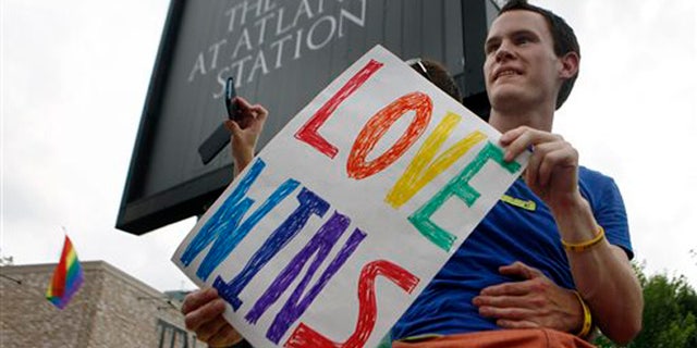 Daniel Hicks sits on a pillar with his boyfriend to watch the local crowd celebrate the U.S. Supreme Court rulings on two landmark gay rights cases surrounding same-sex marriage