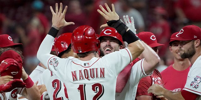 
Tyler Naquin #12 and Mike Moustakas #9 of the Cincinnati Reds celebrate after Moustakas hit a walk-off sacrifice fly in the ninth inning to beat the New York Mets 1-0 at Great American Ball Park on July 05, 2022 in Cincinnati, Ohio. 