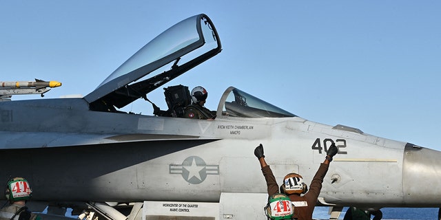 A crew member directs an F/A-18 Hornet fighter jet as it prepares to take off from the deck of the US Nimitz-class nuclear-powered aircraft carrier USS Harry S. Truman, during a NATO vigilance activity NEPTUNE SHIELD 2022 (NESH22) on eastern Mediterranean Sea on May 23, 2022. 