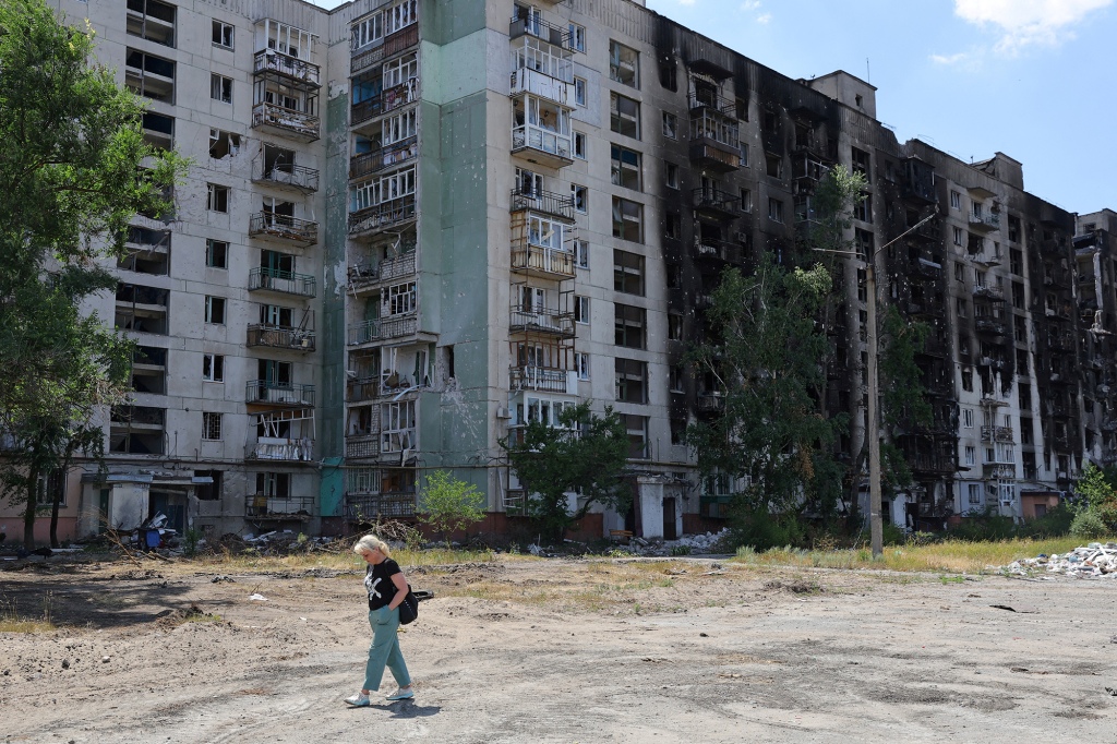 A local resident walks past an apartment building heavily damaged during Ukraine-Russia conflict in the city of Sievierodonetsk in the Luhansk Region, Ukraine on July 1, 2022.