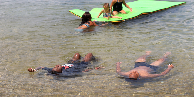 A family relaxes in the cool waters of Mashpee Pond on Cape Cod during a summer heat wave. 