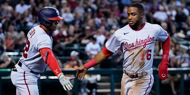 The Washington Nationals' Victor Robles (16) is congratulated by Juan Soto after Robles scored against the Arizona Diamondbacks during the third inning Saturday, July 23, 2022, in Phoenix, Ariz.