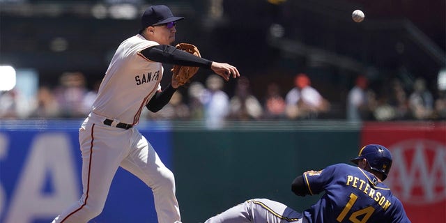 San Francisco Giants second baseman Wilmer Flores, left, throws to first base after forcing Milwaukee Brewers' Jace Peterson (14) out at second base on a double play hit into by Hunter Renfroe during the second inning of a baseball game in San Francisco, Sunday, July 17, 2022. 