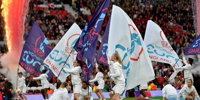 Girls wave flags on the pitch during the opening ceremony before the Women Euro 2022 opening soccer match between England and Austria at Old Trafford in Manchester, England, Wednesday, July 6, 2022. 