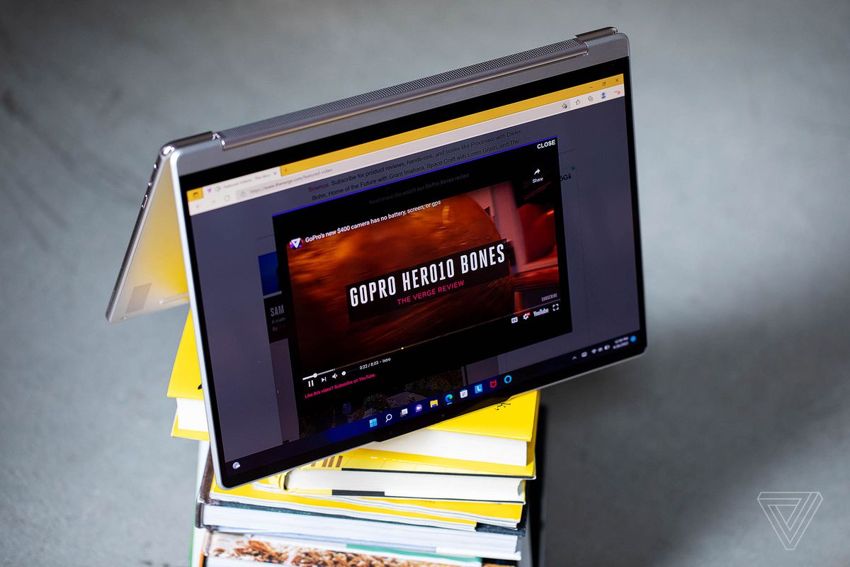 The Lenovo Yoga 9i in tent mode on top of a stack of books.