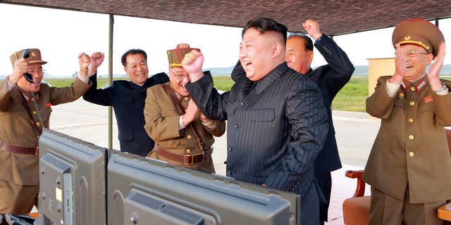 In this undated photo provided by the North Korean government, leader Kim Jong Un celebrates what is said to be the first successful test launch of an intermediate rang Hwasong-12 missile.