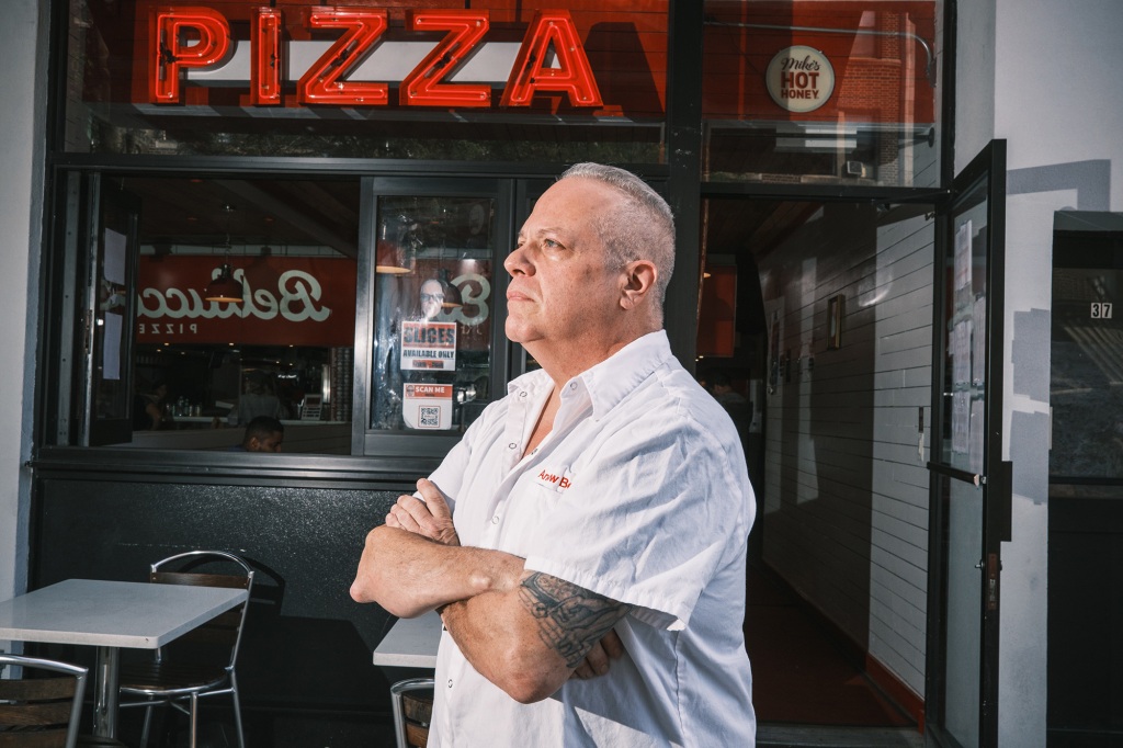 Andrew Bellucci standing, arms folded, in front of Bellucci's Pizzeria in Astoria, Queens.