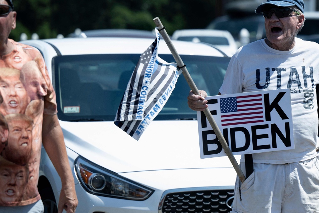 A supporter of former US President Donald Trump holds up a sign as the motorcade of US President Joe Biden drives to the former location of the Brayton Point Power Station in Somerset.