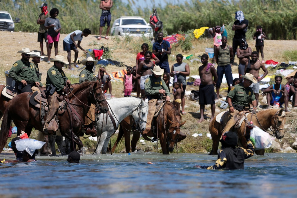 The agents on horseback were using their animals to block the migrants' entry. 