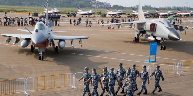 Chinese Air Force personnel march past the Chinese military's J10C fighter and JH-7A2 fighter bomber during 13th China International Aviation and Aerospace Exhibition, also known as Airshow China 2021, Wednesday, Sept. 29, 2021, in Zhuhai in southern China's Guangdong province.