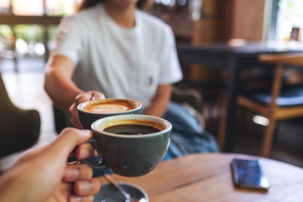 Closeup image of a man and a woman clinking coffee mugs