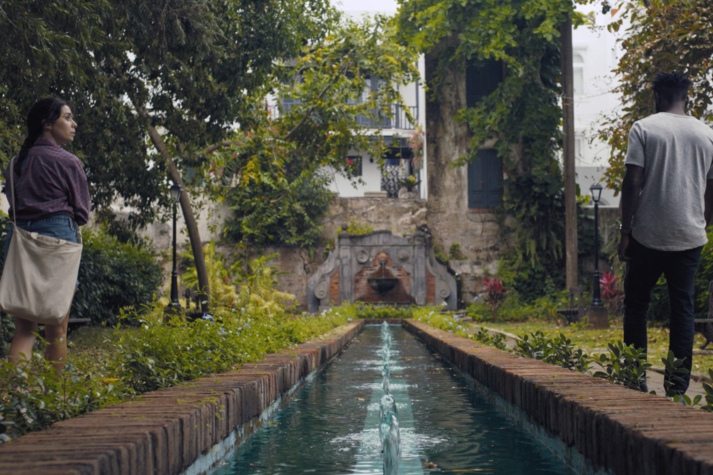 Emma (Cristin Milioti) and Noah (William Jackson Harper) stroll alongside a canal and a temple in ruins. 