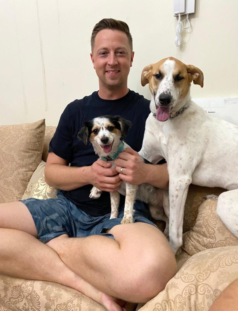 Chief Petty Officer Matt Johnson sits with his two rescue dogs, Ruby and Sunny.