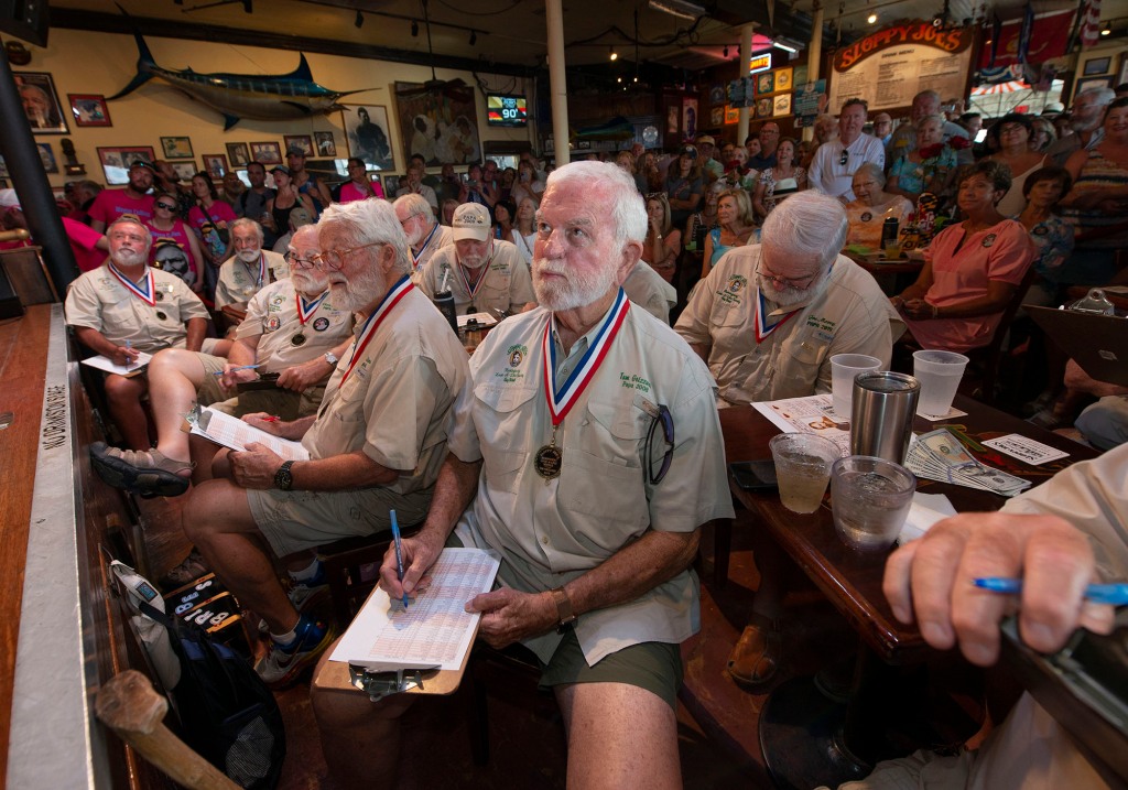 In this photo provided by the Florida Keys News Bureau, Tom Gizzard, center, the 2008 winner of the "Papa Hemingway Look-Alike Contest and other previous winners/judges examine contestants during the first round of the 2022 contest Thursday, July 21, 2022, at Sloppy Joe's Bar in Key West, Fla.