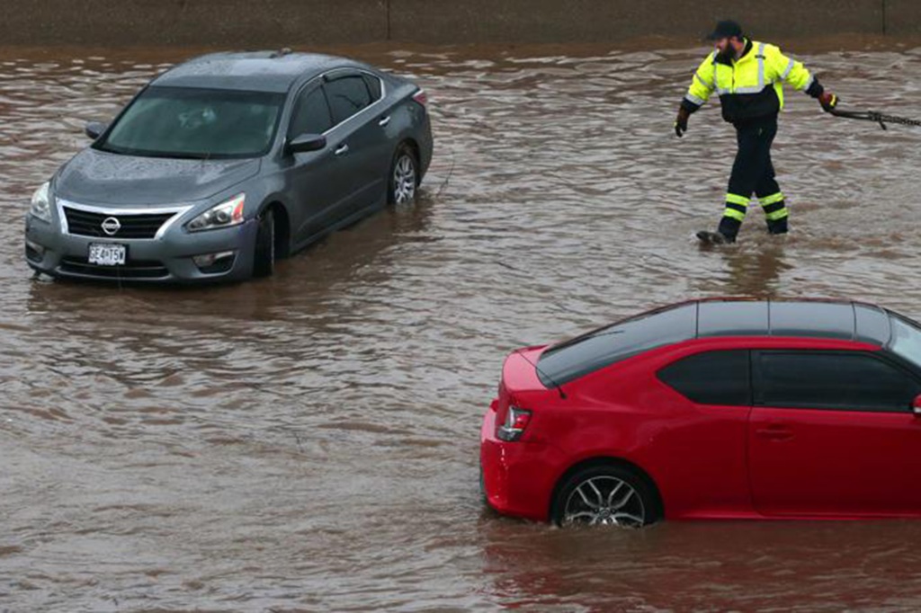 A tow truck driver moves to clear a flooded car as another rolls along Interstate 70 at Mid Rivers Mall Drive in St. Peters after heavy rain fell through Monday night and into the morning on Tuesday, July 26, 2022. (Robert Cohen/St. Louis Post-Dispatch via AP)