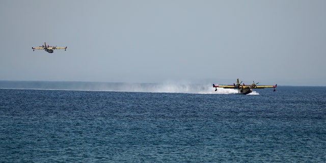 Firefighting aircrafts load water from the sea during a forest fire near the beach resort of Vatera, on the eastern Aegean island of Lesvos, on Saturday, July 23, 2022. Locals were evacuated on Saturday as a wildfire threatened properties near a beach in the southern part of the island, which is also a popular tourist attraction. (AP Photo/Panagiotis Balaskas)