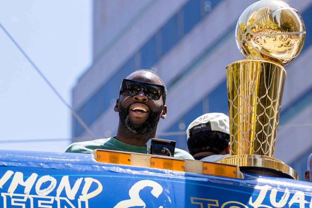 Golden State Warriors' Draymond Green stands next to the Larry O'Brien trophy during the NBA Championship parade in San Francisco, Monday, June 20, 2022, in San Francisco.