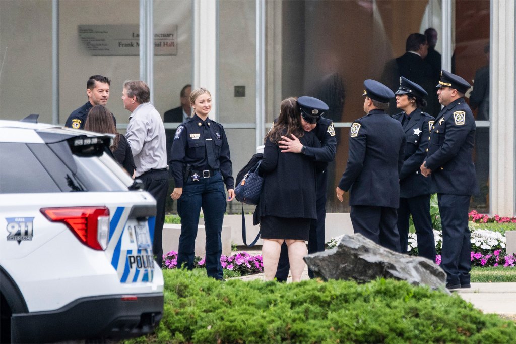 Mourners and police officers hug before entering the funeral service for Jacquelyn Sundheim.