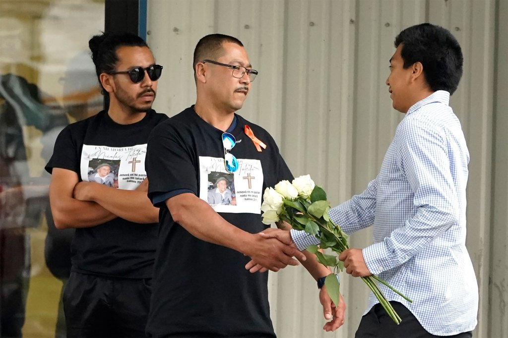 A man carrying flowers is greeted at a private viewing and funeral service for Nicolas Toledo-Zaragoza.