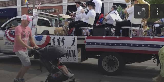 A Fourth of July parade-goer runs for cover after gunfire was heard at the parade Monday morning, July 4, 2022, in a suburb of Chicago. (Lynn Sweet/Chicago Sun-Times via AP)