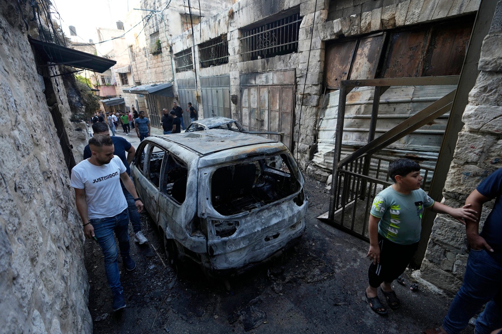 Palestinians inspect the damage to a car.