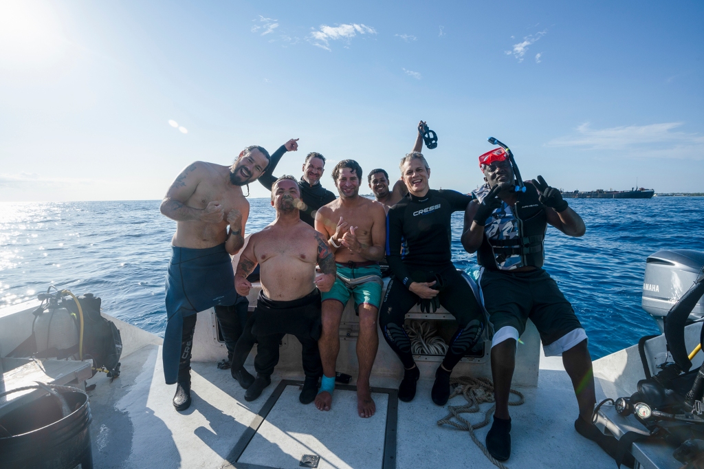 The crew from "Jackass." They're on a boatg in the water and smiling for the camera.