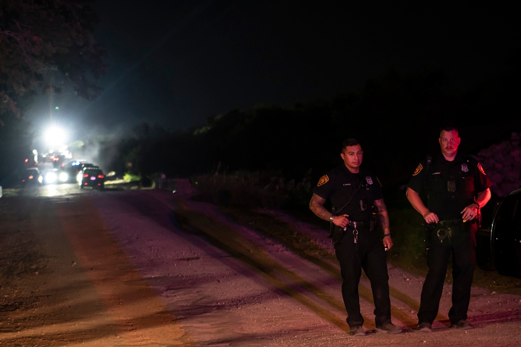 Police guard an area at the scene where a tractor-trailer was discovered with migrants inside outside San Antonio, Texas on June 27, 2022.