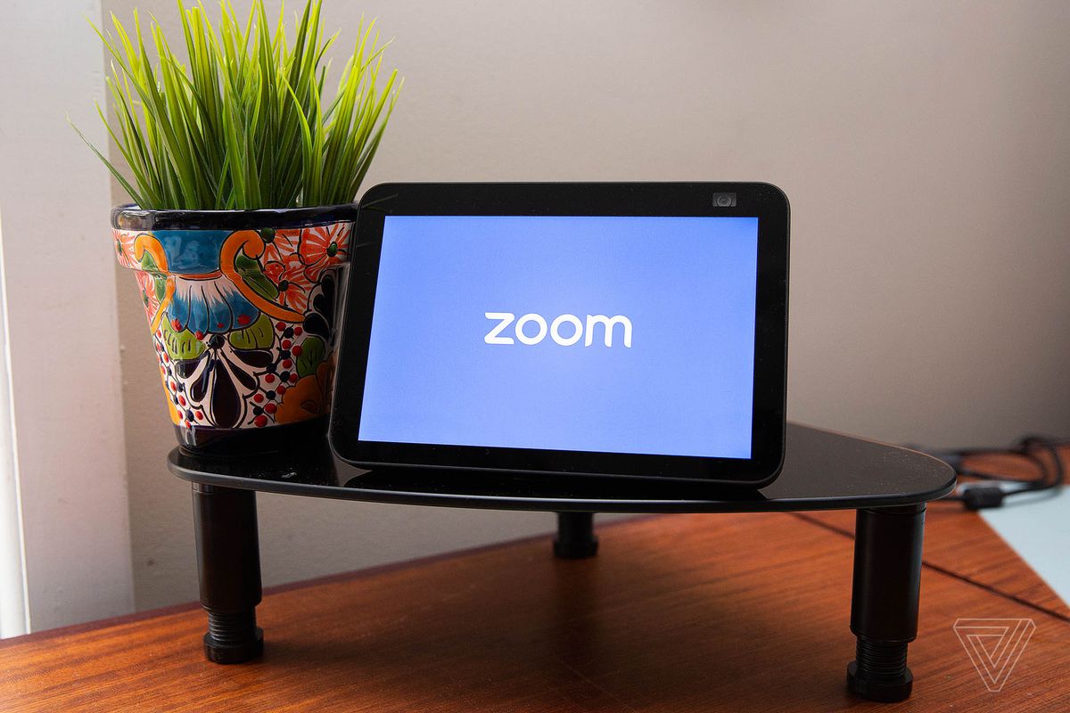 The Zoom loading screen displayed on a smart display on a coffee table beside a potted plant.