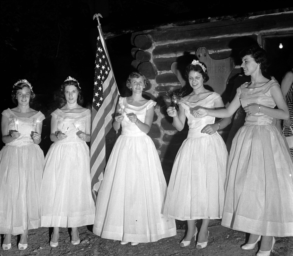 Pageant contestants stand on a stage and light sparklers during The Queen of Candles, circa 1955.