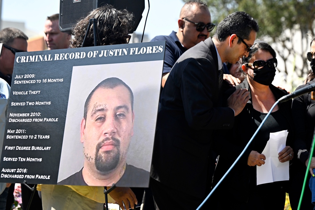 Olga Garcia, mother of slain officer Joseph Santana walks past a poster of suspect Justin Flores as she spoke during a press conference about the recall of Los Angeles district Attorney George Gascon