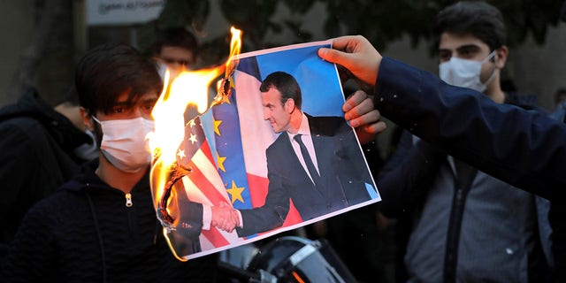 Iranian protesters burn a picture of French President Emmanuel Macron and President Donald Trump during a protest against Macron and the publishing of caricatures of the Prophet Muhammad they deem blasphemous, in front of French Embassy in Tehran, Iran, Wednesday, Oct. 28, 2020. 