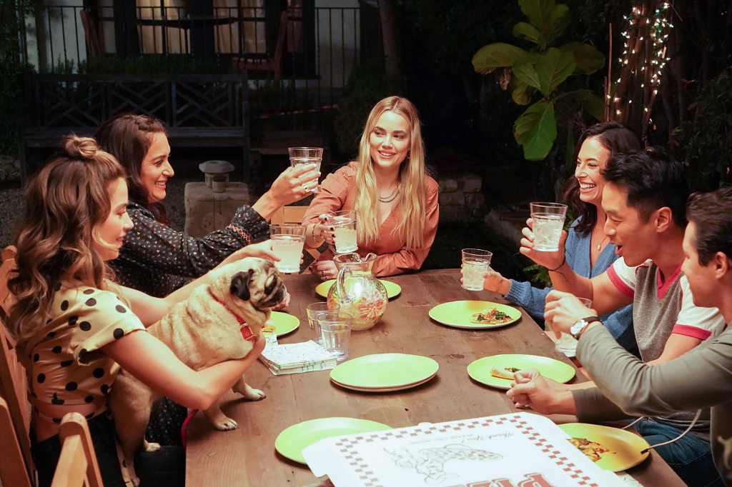Psychic Maggie (Rebecca Rittenhouse) with pals, Amy (Angelique Cabral), Jessie (Chloe Bridges) and Dave (Leonardo Nam) sit around a dinner table smiling. 