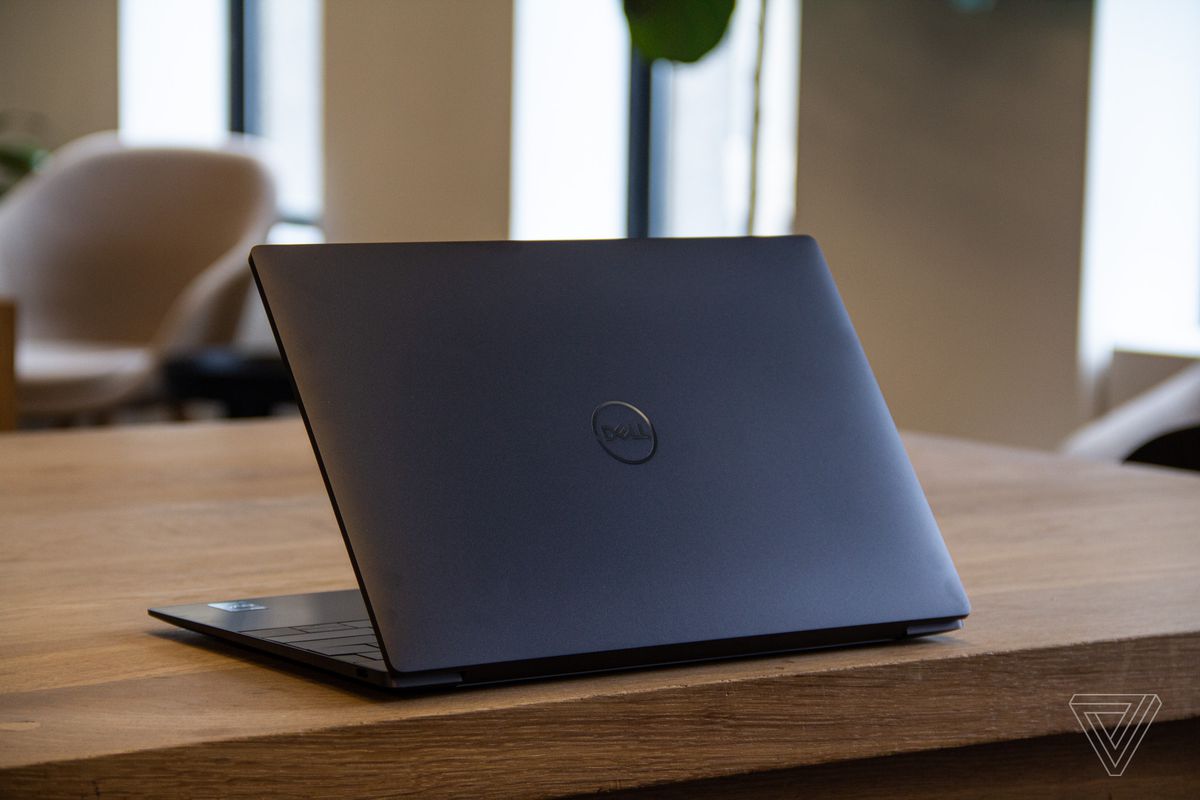 The Dell XPS 13 Plus on a wooden table half open facing away from the camera.