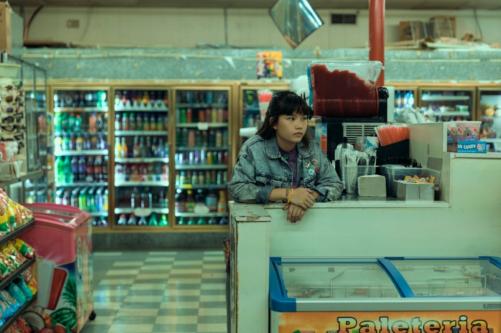 Erin Tieng (Riley Lai Nelet) stands in a convenience store looking bored. 