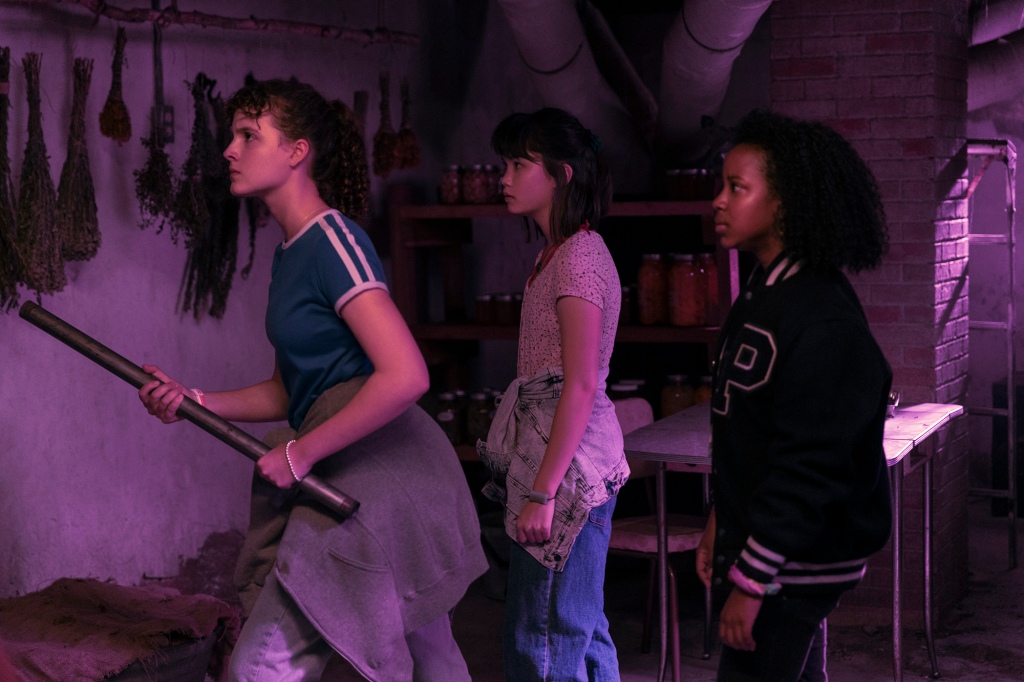 Fina Strazza, Riley Lai Nelet, and Camryn Jones in "Paper Girls" walk in a line holding weapons. 