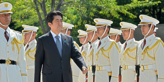 Japanese Prime Minister Shinzo Abe reviews honor guards at the defence ministry in Tokyo on Sept. 12, 2013.