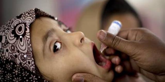 In this photo taken in February 2015, a Pakistani health worker gives a polio vaccine to a child at a bus terminal in Rawalpindi, Pakistan.