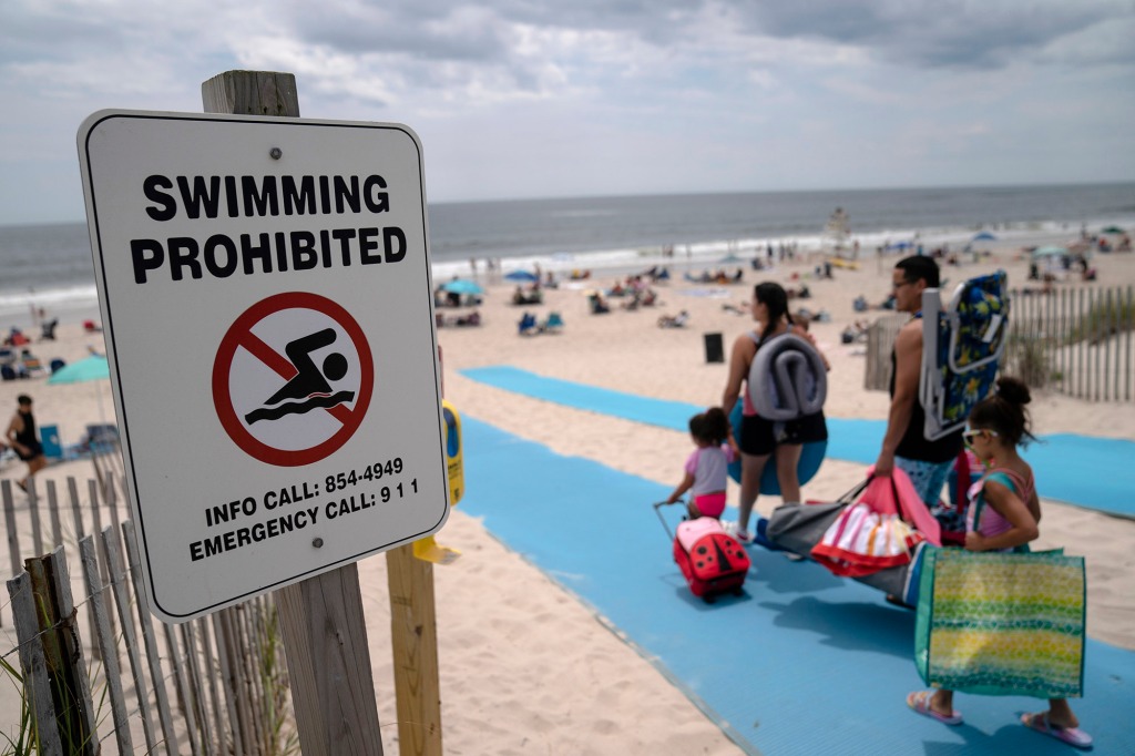 Beach-goers enjoy the surf at Smith Point County Park, a Long Island beach where shark bit a lifeguard 10 days earlier, Friday, July 15, 2022, in Shirley, N.Y.