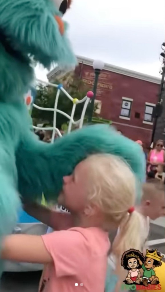 The employee in the costume instead bends down to wrap a white child in a warm embrace.