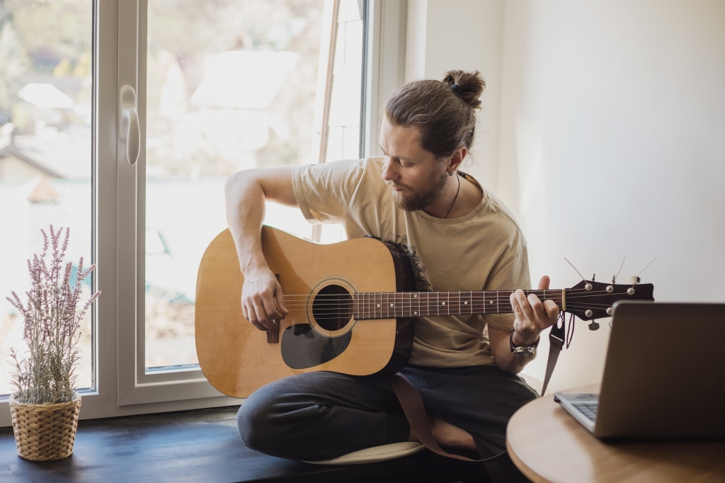 A man plays guitar inside his home.