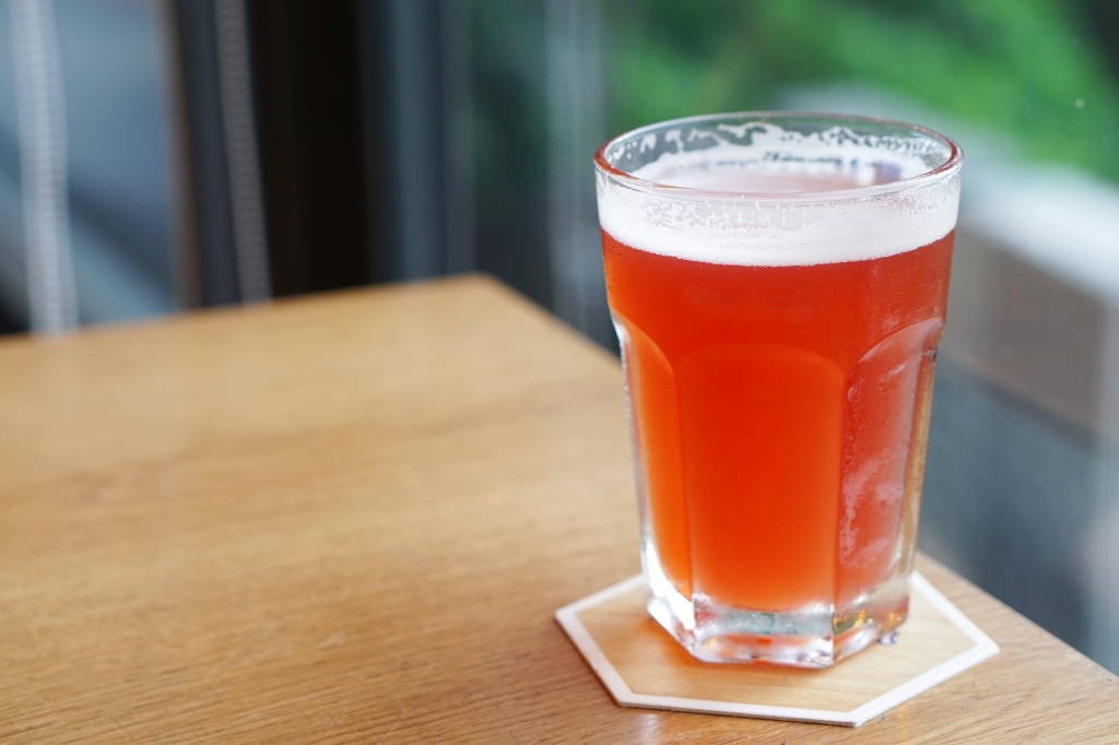 A fruit cider sits on a coaster.