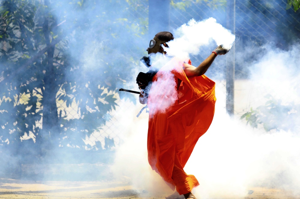 A man throws back a tear gas canister after it was fired by police to disperse protesters in Colombo, Sri Lanka, Saturday, July 9, 2022.