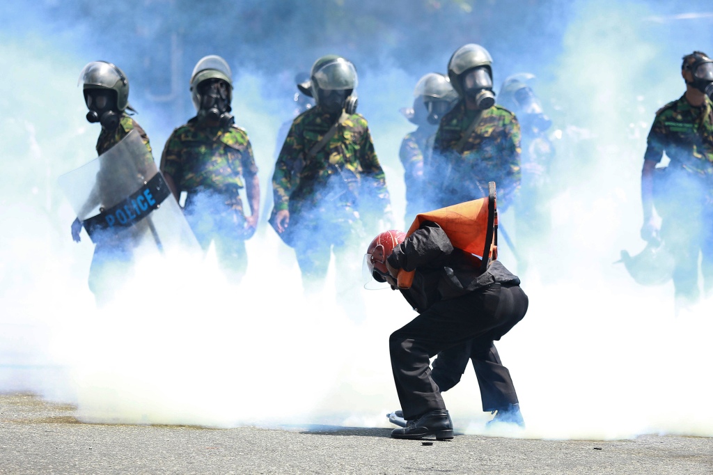 A man picks up a tear gas canister to throw it away after police fired it to disperse the protesters in Colombo, Sri Lanka, Saturday, July 9, 2022.