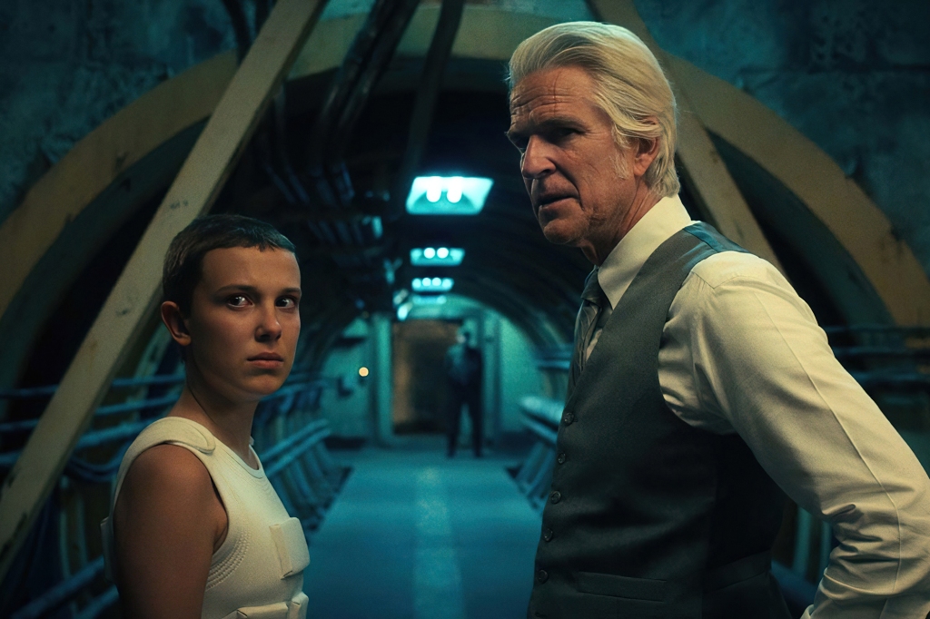 Eleven (Millie Bobby Brown) with Papa (Matthew Modine) stand in a lab. 