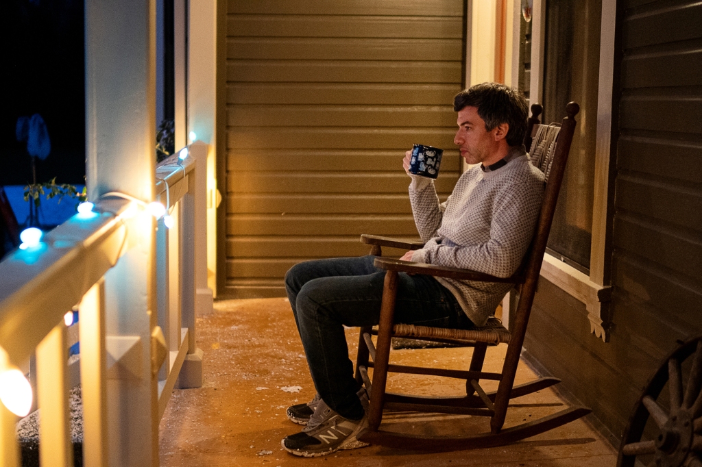 Nathan Fielder in a rocking chair on a porch. 