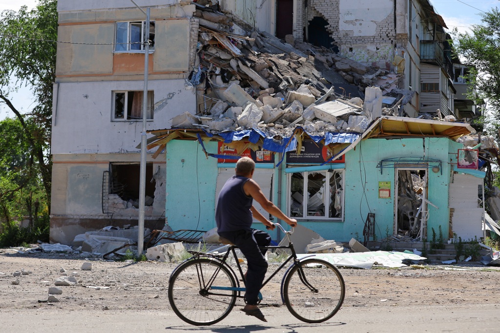 A local resident rides a bicycle past an apartment building heavily damaged during Ukraine-Russia conflict in the city of Sievierodonetsk in the Luhansk Region, Ukraine June 30, 2022. REUTERS/Alexander Ermochenko