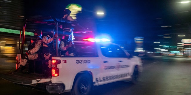 Armed members of the National Guard drive past the site of a burnt collective transport vehicle after it was set on fire by unidentified individuals in Tijuana, Baja California state, Mexico, on August 12, 2022.