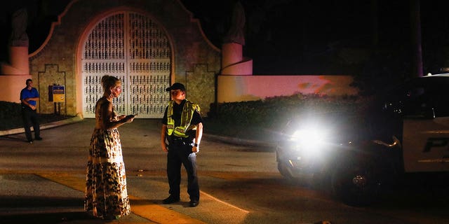 A police officer speaks with a woman outside former President Donald Trump's Mar-a-Lago home, after Trump said that FBI agents raided it, in Palm Beach, Florida, on Aug. 8, 2022.