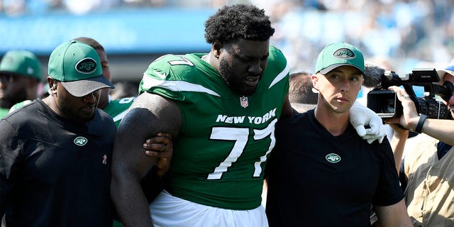 Mekhi Becton #77 of the New York Jets is helped off the field after being injured during the third quarter against the Carolina Panthers at Bank of America Stadium on Sept. 12, 2021 in Charlotte, North Carolina. 