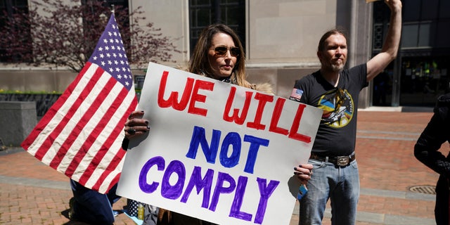 A protestor carries a sign reading "We Will Not Comply" during a demonstration outside the Virginia State Capitol